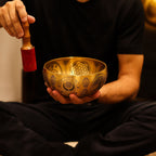 Personne utilisant un bol chantant tibétain avec un maillet pour produire des vibrations apaisantes
