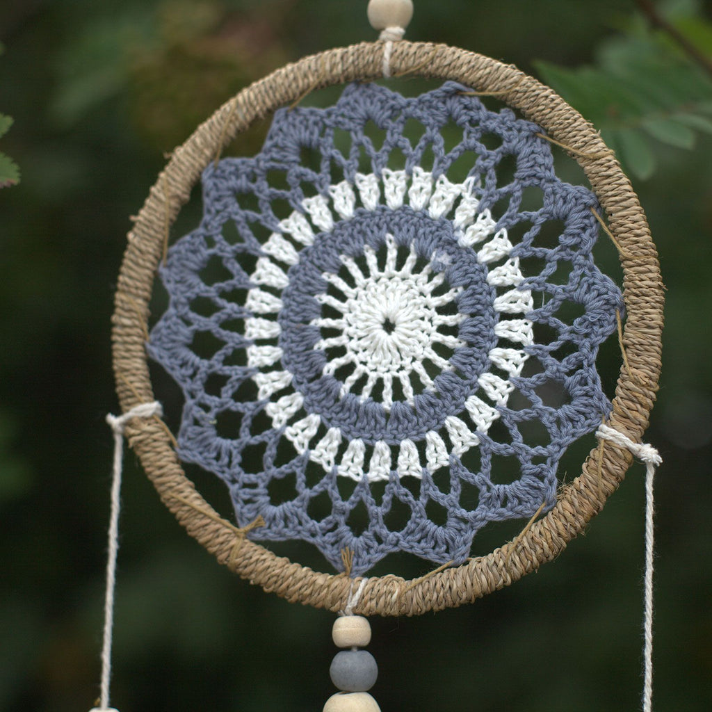 Gros plan sur le tissage circulaire d’un attrape-rêves gris esprit élémentaire, symbole d’harmonie et d’équilibre