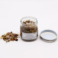 bain floral naturel aux plantes botaniques dans un pot en verre pour rituel de relaxation. Pot ouvert avec un couvercle à côté du pot et bain floral éparpillé de l'autre côté