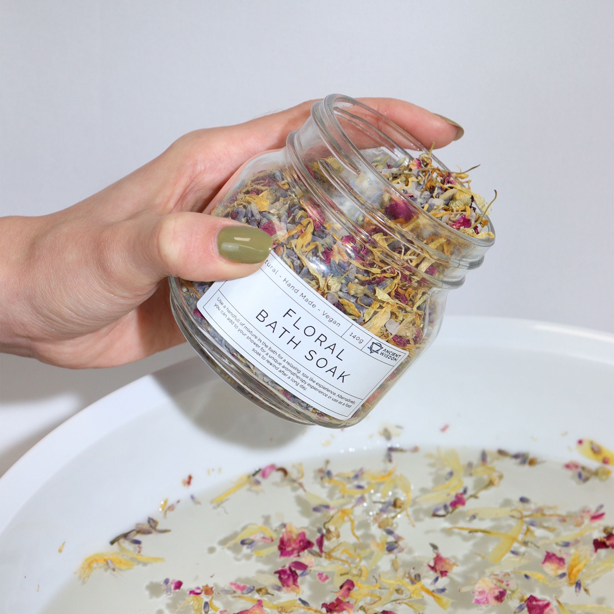 main tenant un bain floral naturel avec plantes botaniques pour relaxation, et en versant un peu dans de l'eau