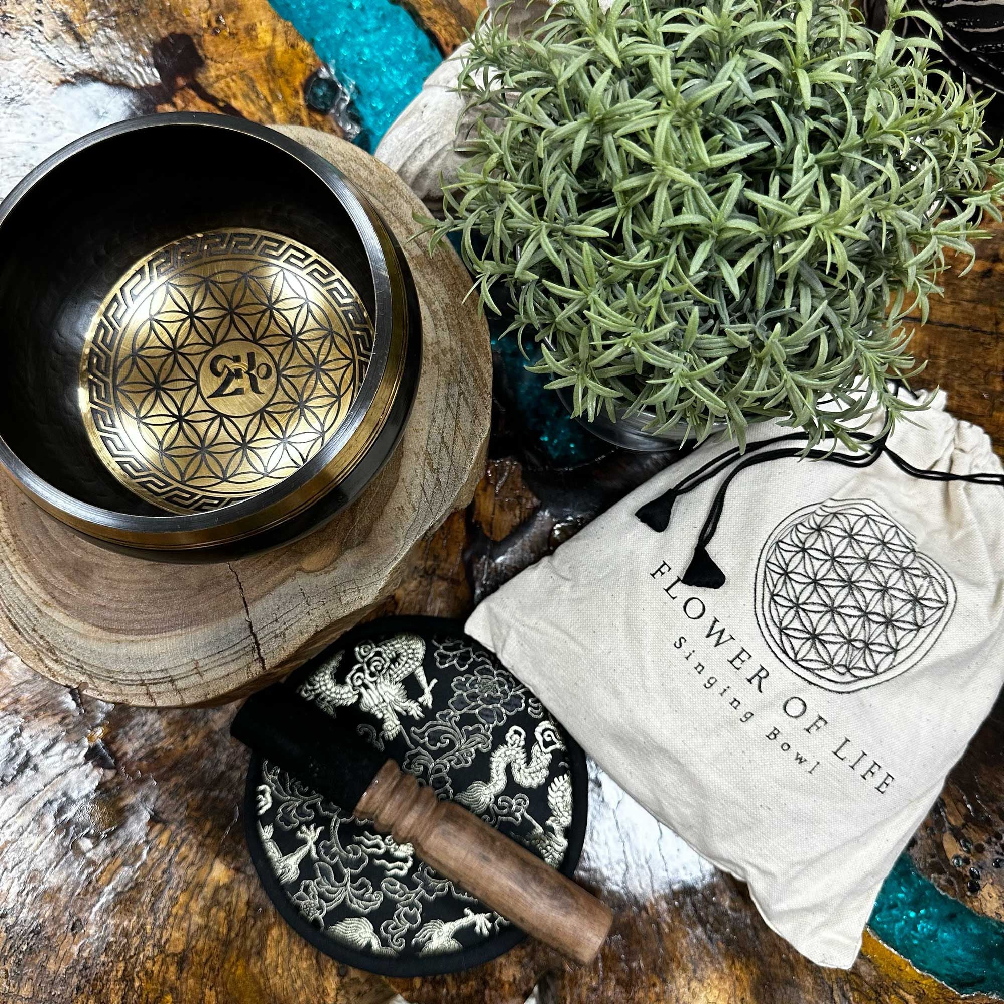 Bol chantant Fleur de vie posé sur bois avec plante, maillet et pochette, ambiance naturelle pour méditation et harmonisation