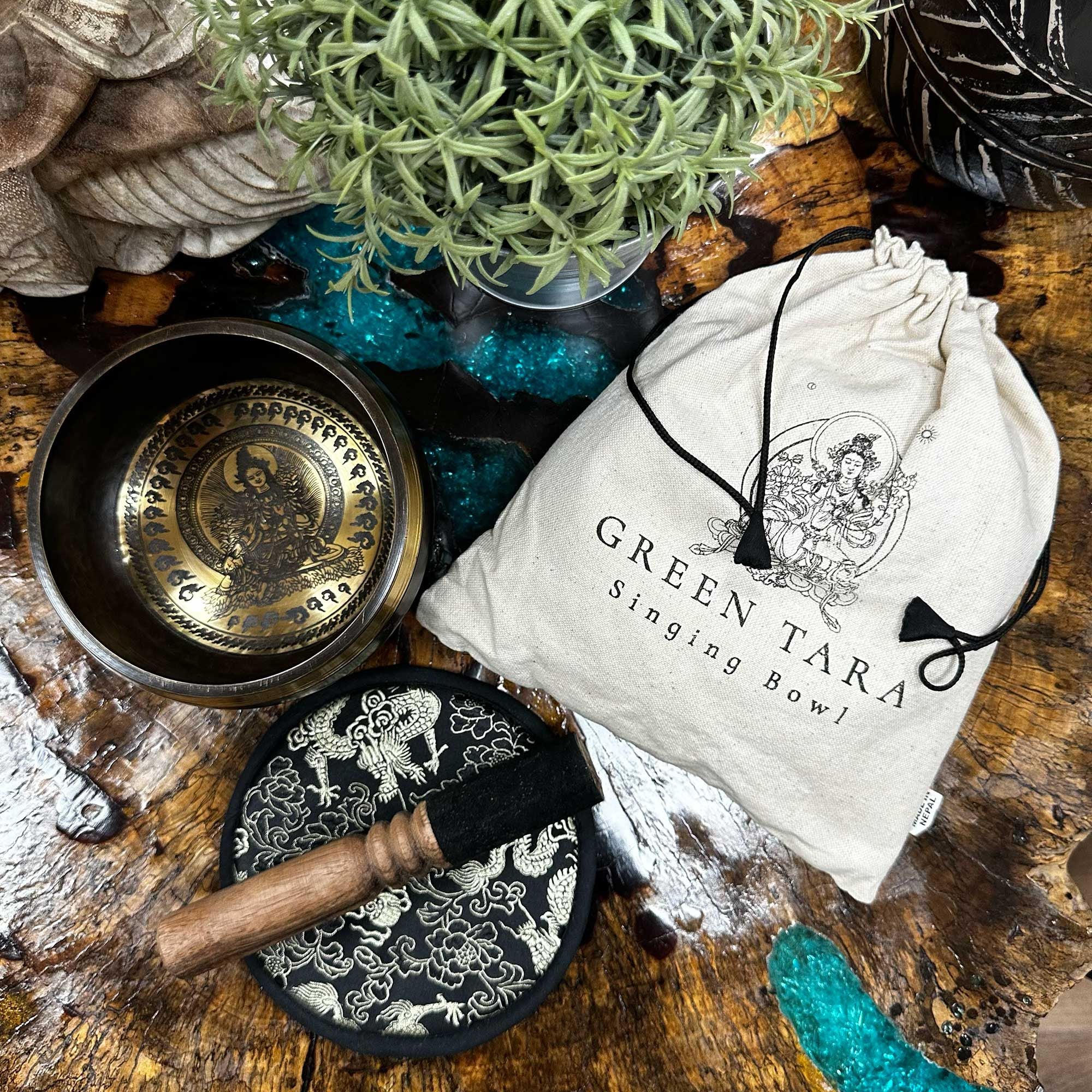 Bol chantant green tara posé sur bois avec plante, maillet et pochette, ambiance naturelle pour méditation et harmonisation