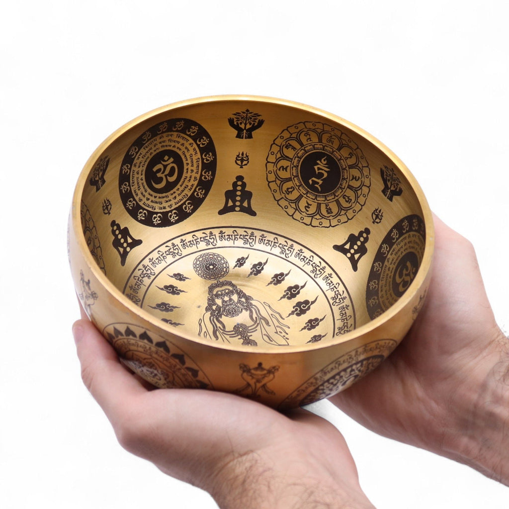 Bol chantant tibétain en laiton gravé tenu dans une main montrant sa taille compacte et ses détails spirituels