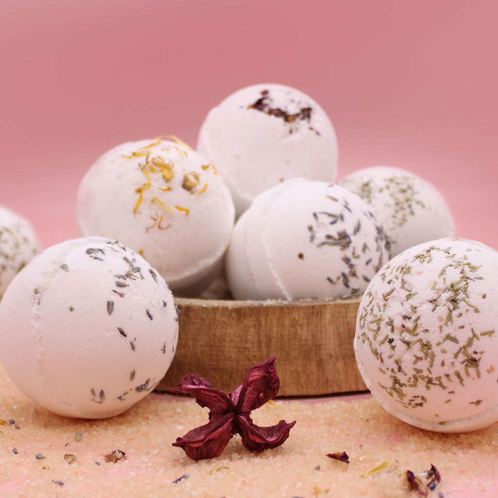 Bombes de bain artisanales au sel de l’Himalaya avec fleurs séchées sur fond rose, ambiance bien-être et relaxation