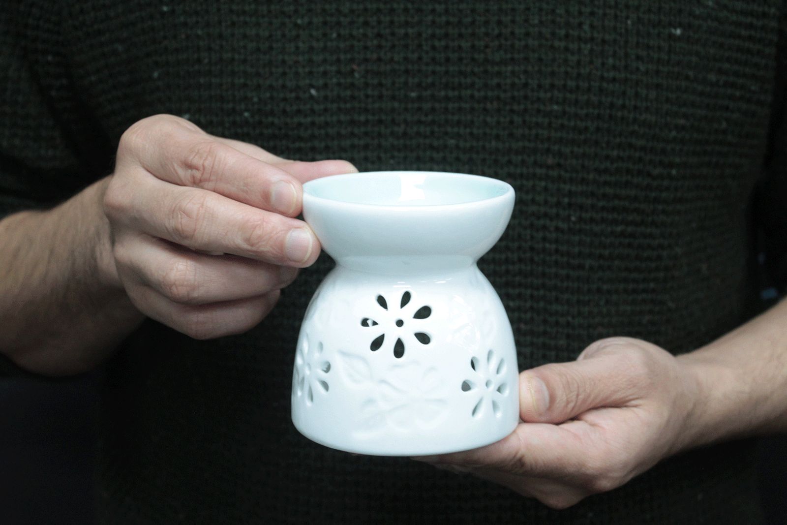 personne tenant un brûleur à huile en céramique blanche utilisé pour diffusion de parfum et ambiance zen