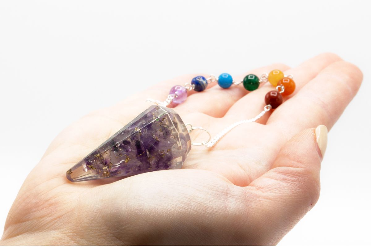 Pendule orgonite amethyste tenu en main pour radiesthésie, divination et travail énergétique