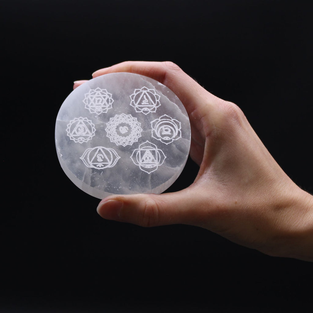 Plaque selenite chakras tenue en main pour recharger les pierres et maintenir un equilibre energetique quotidien