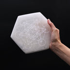 Plaque selenite hexagonale tenue en main pour recharger les pierres et favoriser clarte et concentration