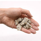 Gros plan sur des morceaux de résine de benjoin naturelle aux teintes blanc gris avec une poignée de résine dans une main pour illustrer la texture et la taille des grains