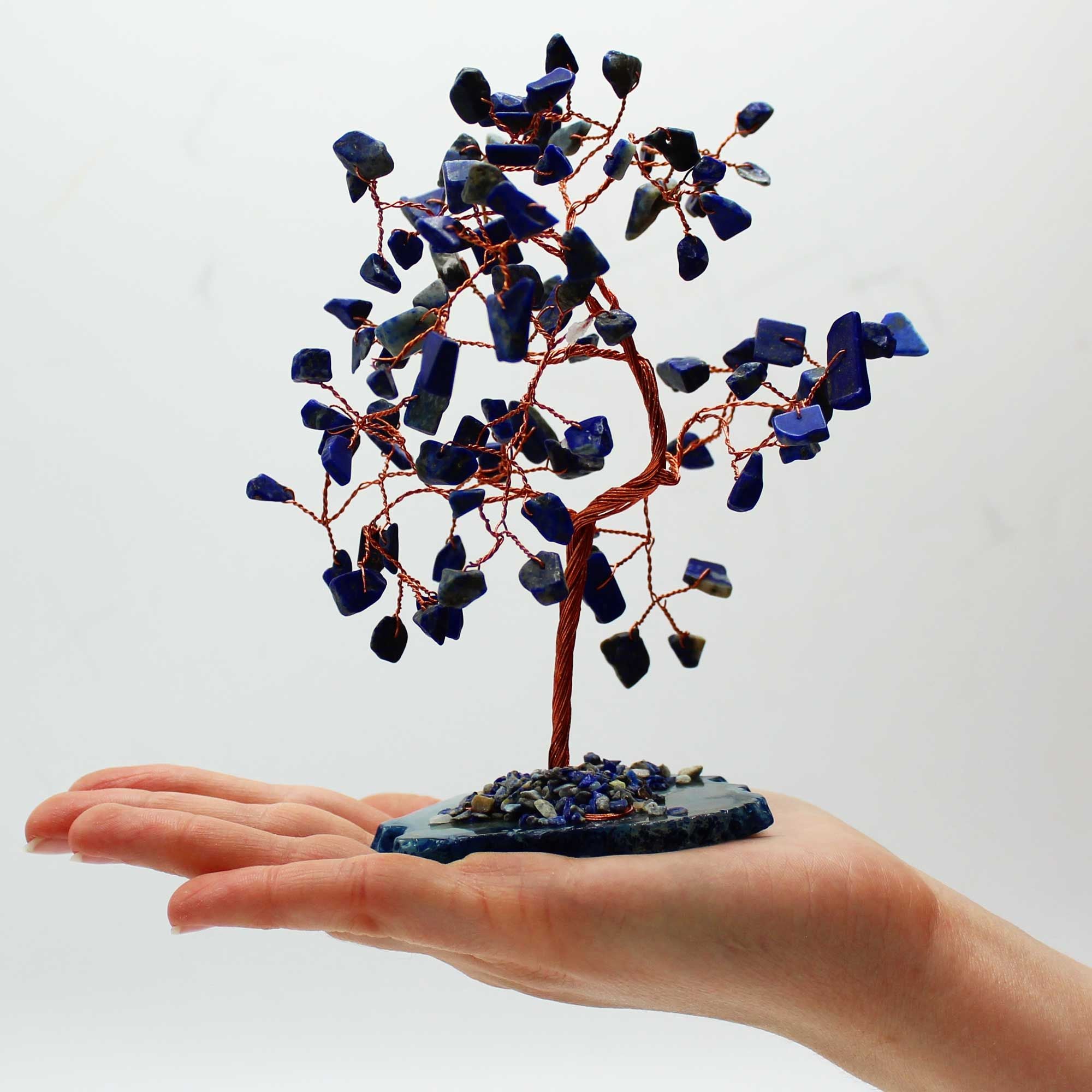 Arbre en sodalite tenu dans une main avec base bleue et pierres naturelles, symbole de calme et clarté mentale