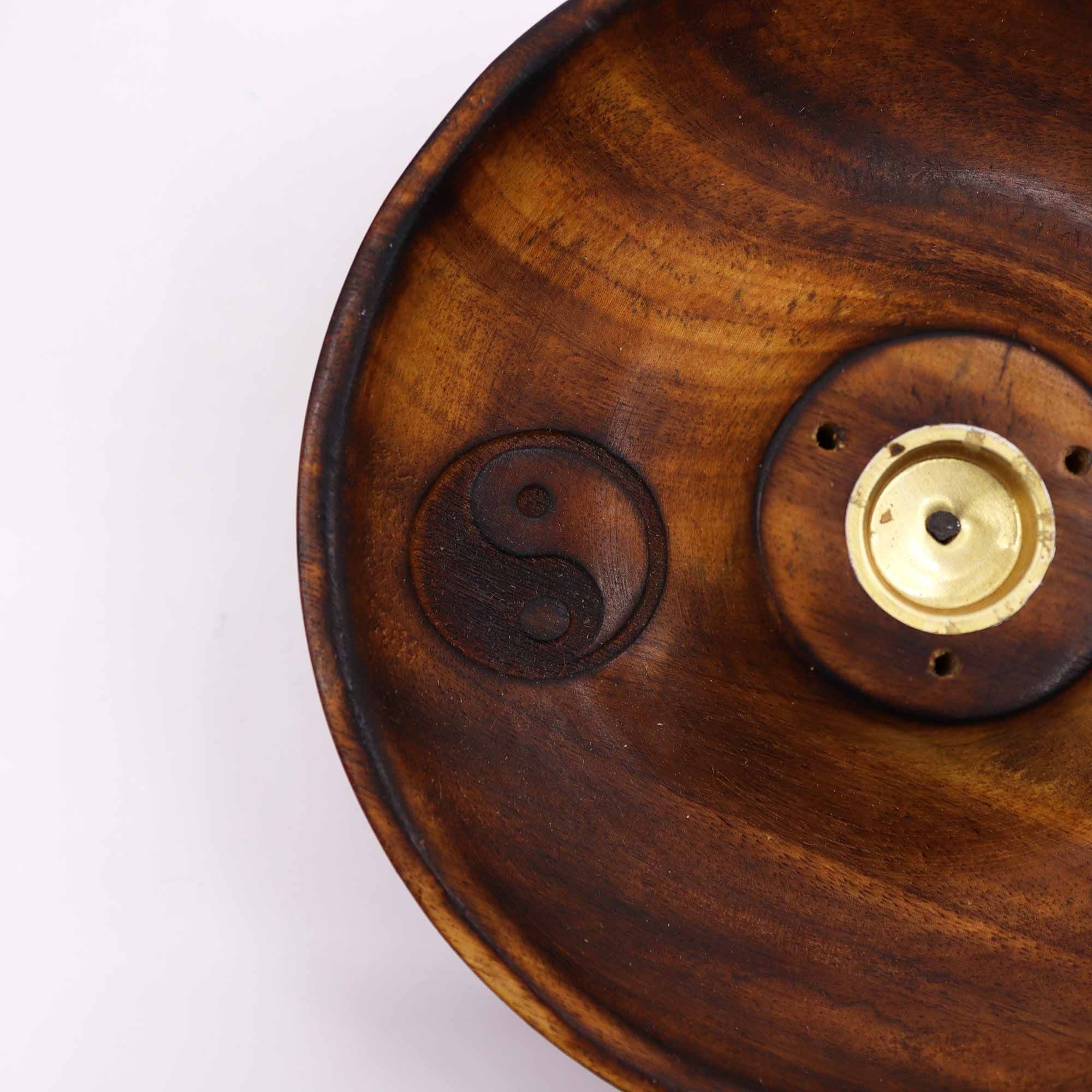 gros plan sur symbole yin yang gravé dans un porte encens artisanal en bois naturel montrant la texture du bois