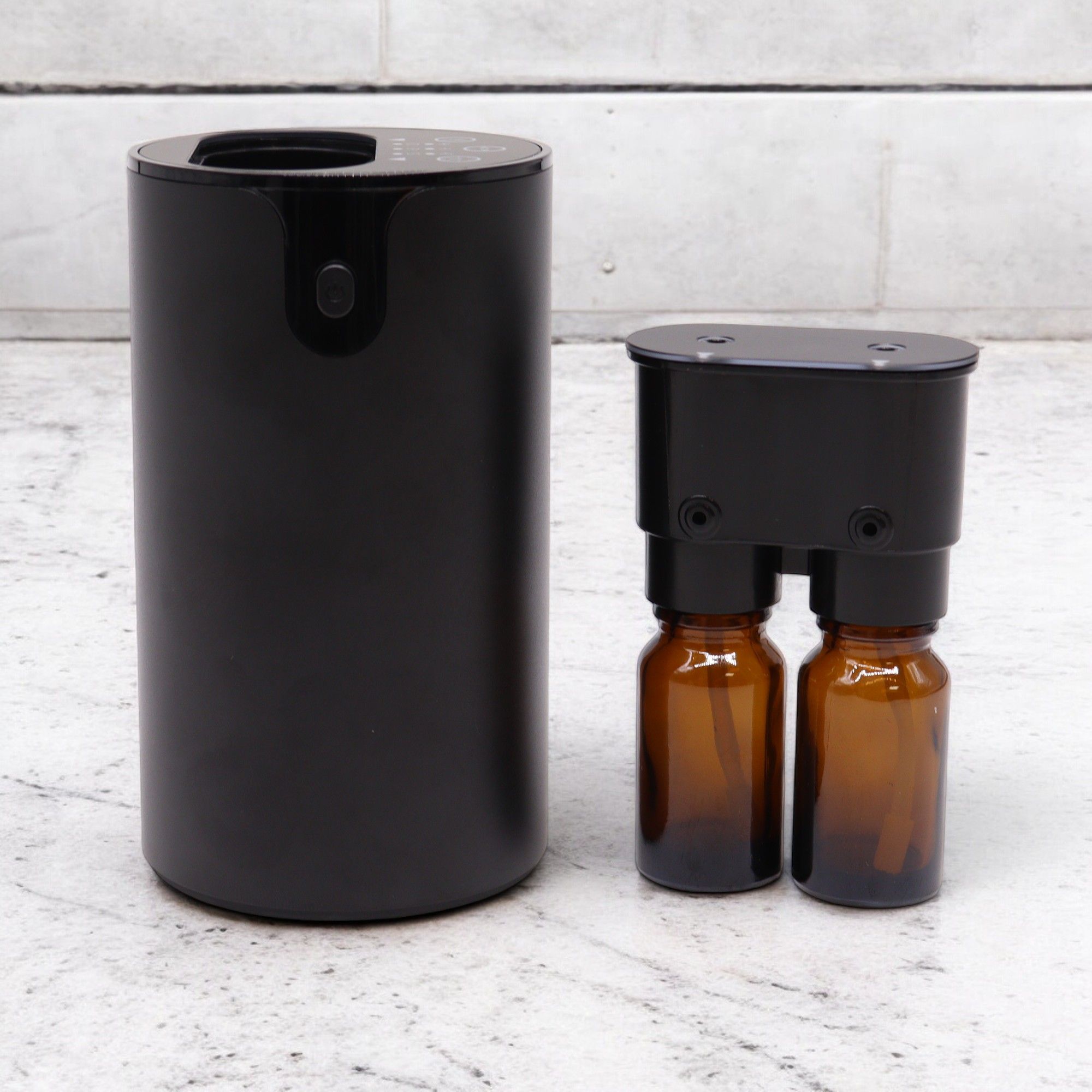 Diffuseur sans eau noir au design minimaliste avec flacons d’huiles essentielles en décoration