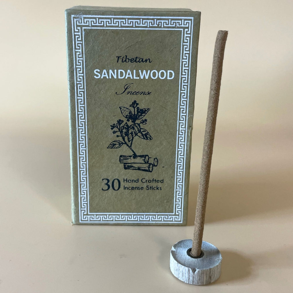 Encens tibétain bois de santal avec bâtonnet posé sur support et coffret vert en arrière-plan
