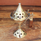 brûleur d’encens en laiton avec manche bois posé sur une table en bois avec encens à côté utilisé pour rituels méditation et parfum d’intérieur