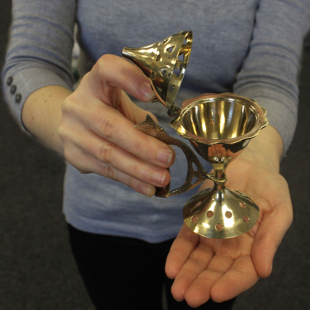 brûleur d’encens en laiton avec manche bois tenu dans les mains montrant sa taille compacte pour autel méditation ou rituel de purification