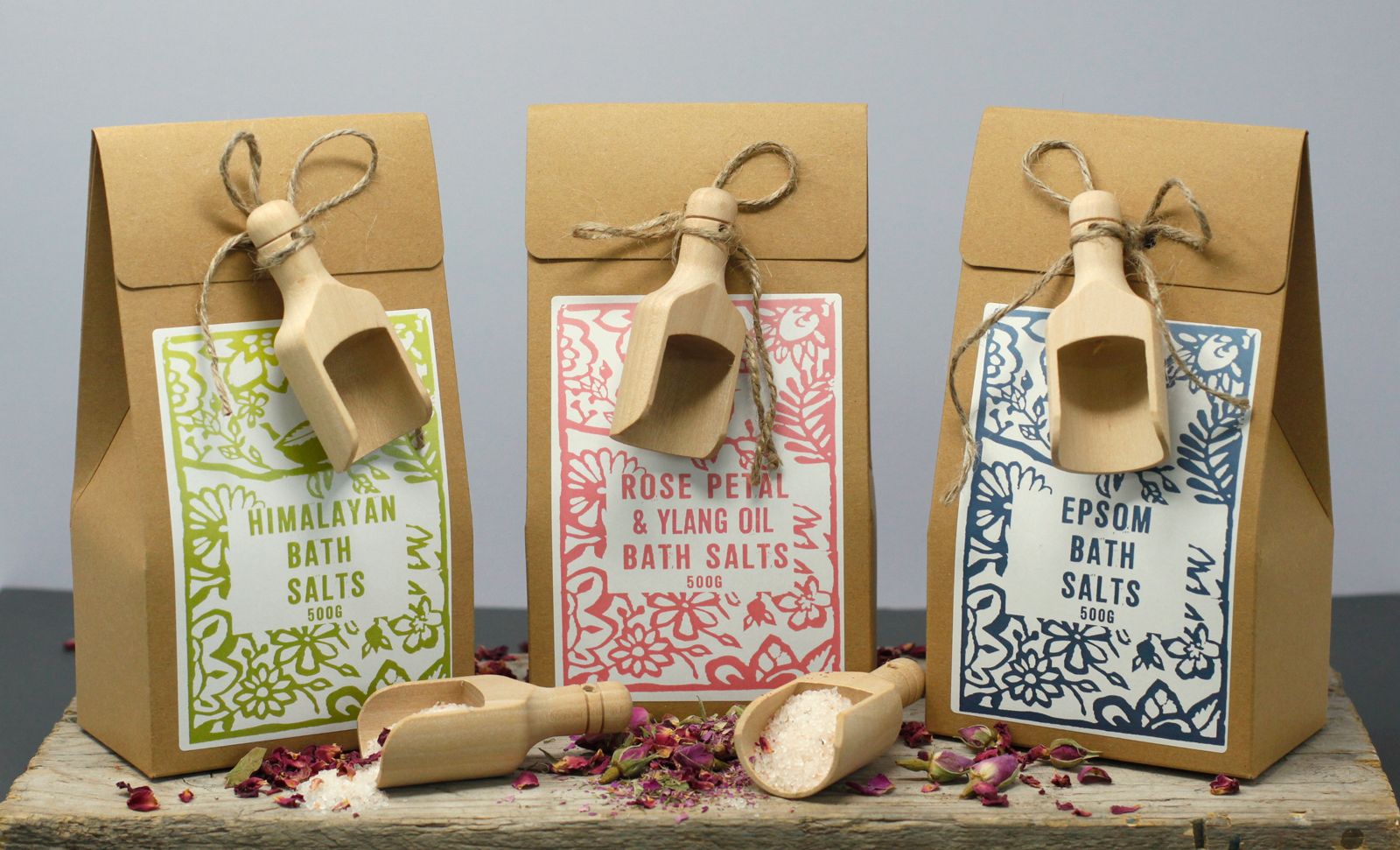 Trois sels de bain 500g Himalaya, rose ylang ylang et epsom alignés avec cuillères en bois et ambiance bien-être