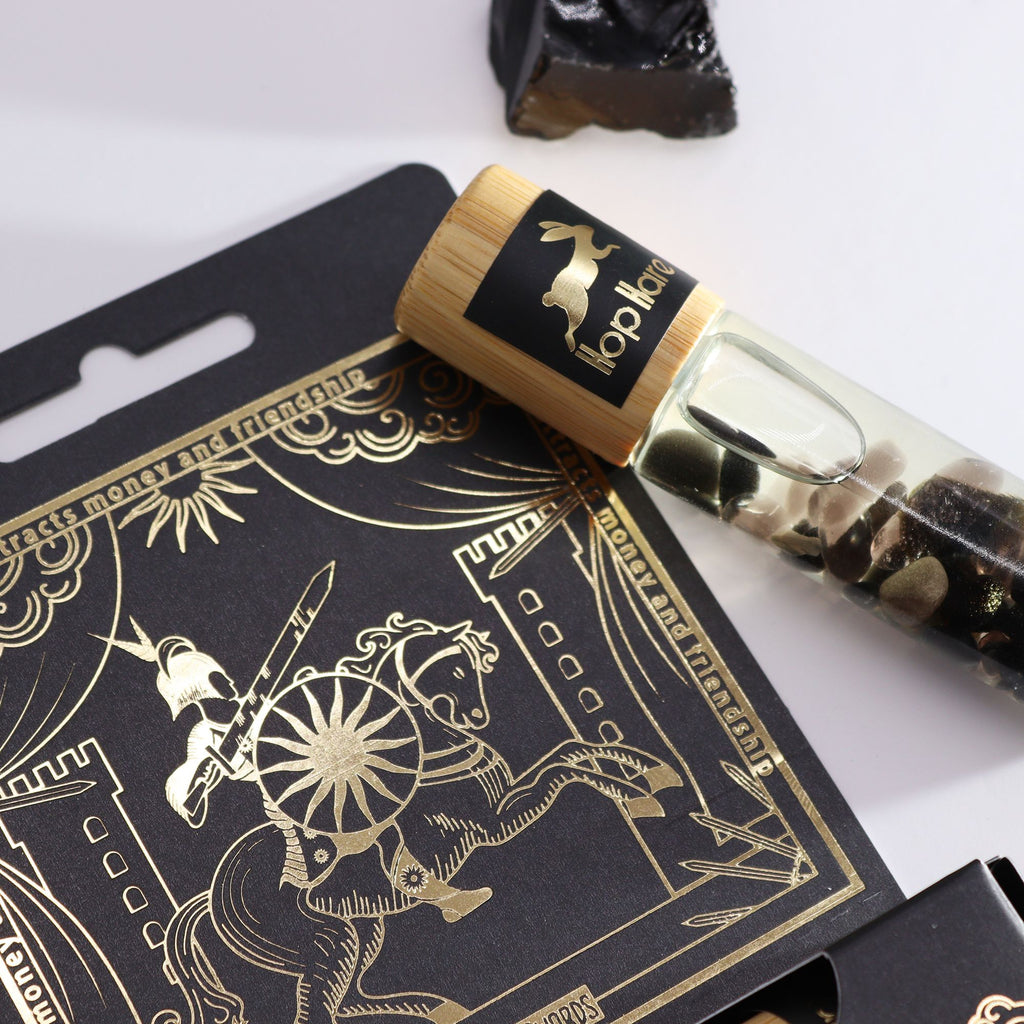 Roll-on Le cavalier aux huiles essentielles et pierre naturelle de tourmaline posé sur son coffret tarot.