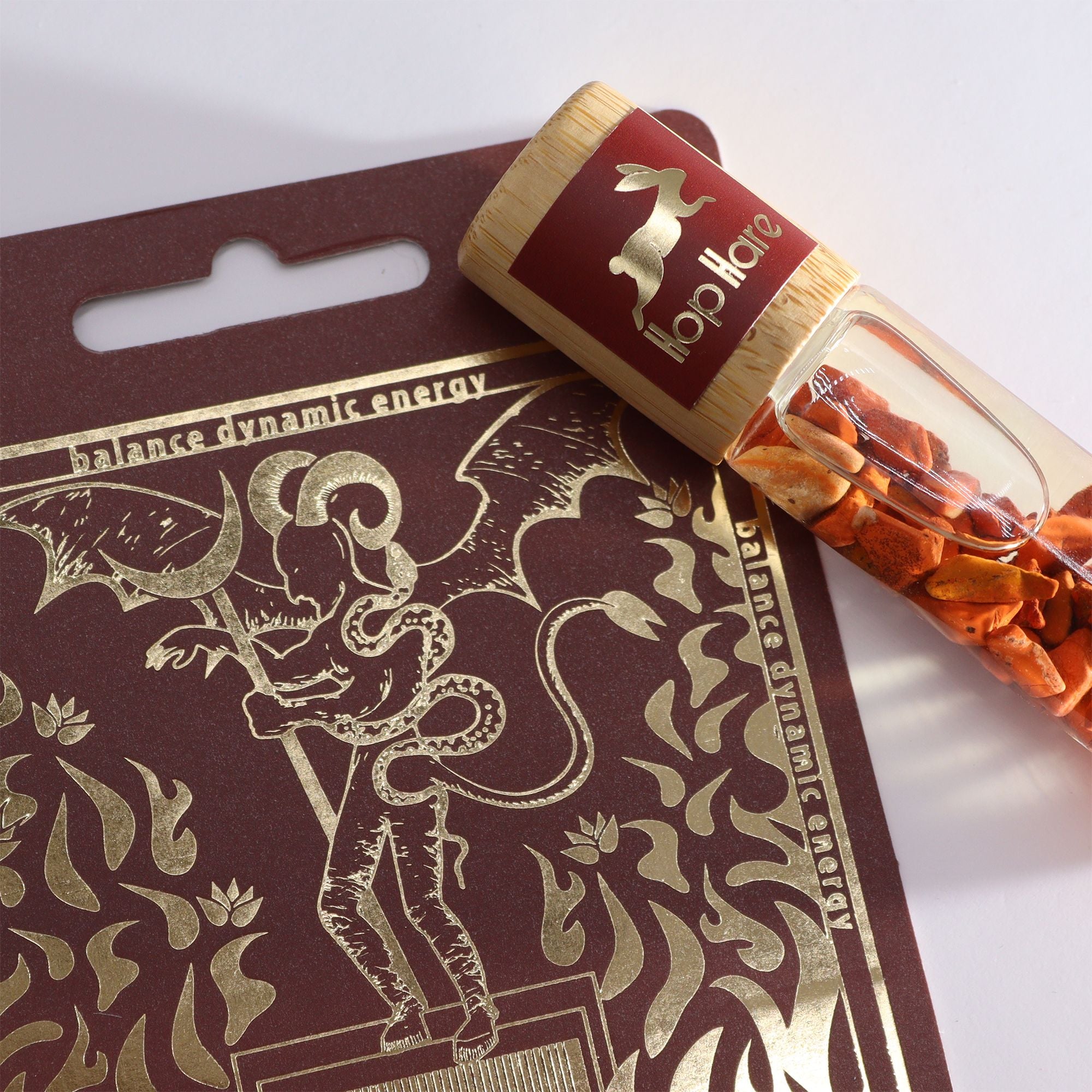 Roll-on Le diable aux huiles essentielles et pierre naturelle jaspe rouge posé sur son coffret tarot.
