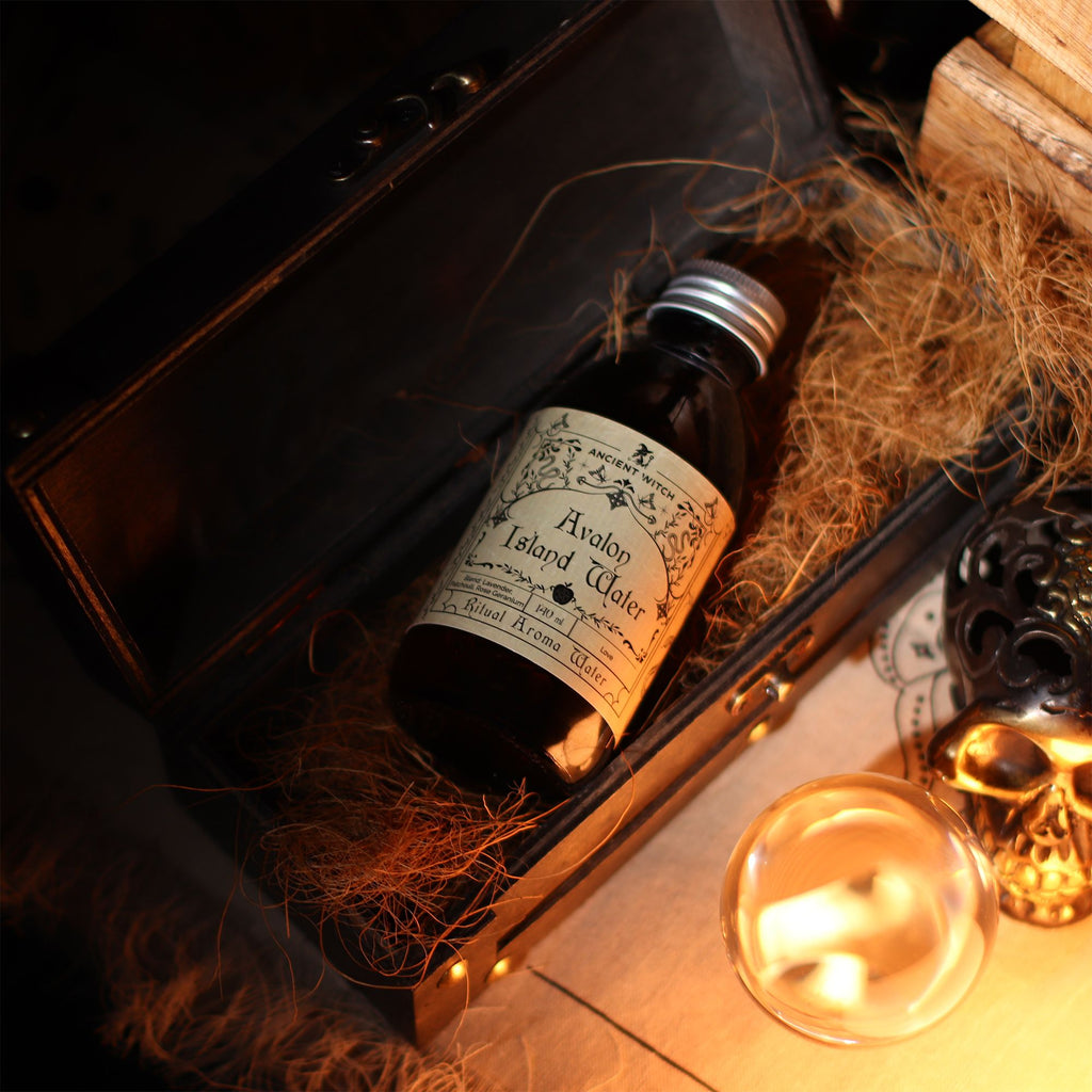 Flacon d’eau rituelle île d'avalon posé dans un coffret avec objets ésotériques, ambiance mystique de rituel spirituel