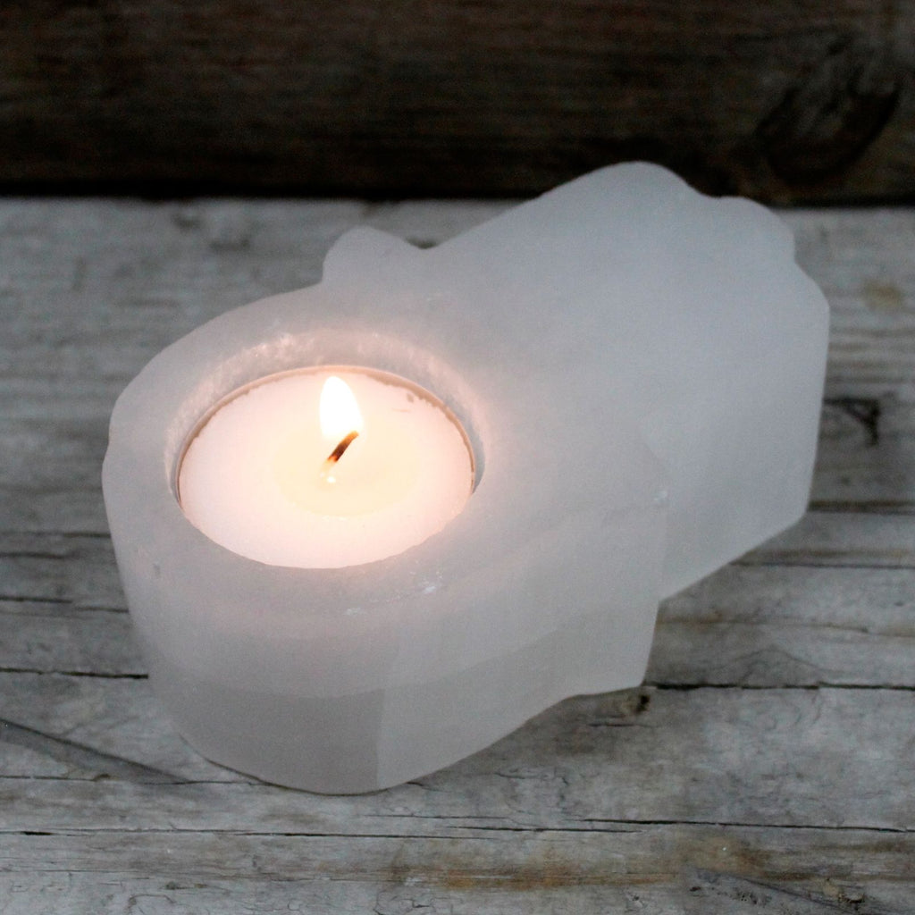 Photophore selenite hamsa avec bougie allumee creant une ambiance chaleureuse et protectrice