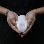 Photophore selenite hamsa tenu en main montrant sa taille compacte et son design protecteur