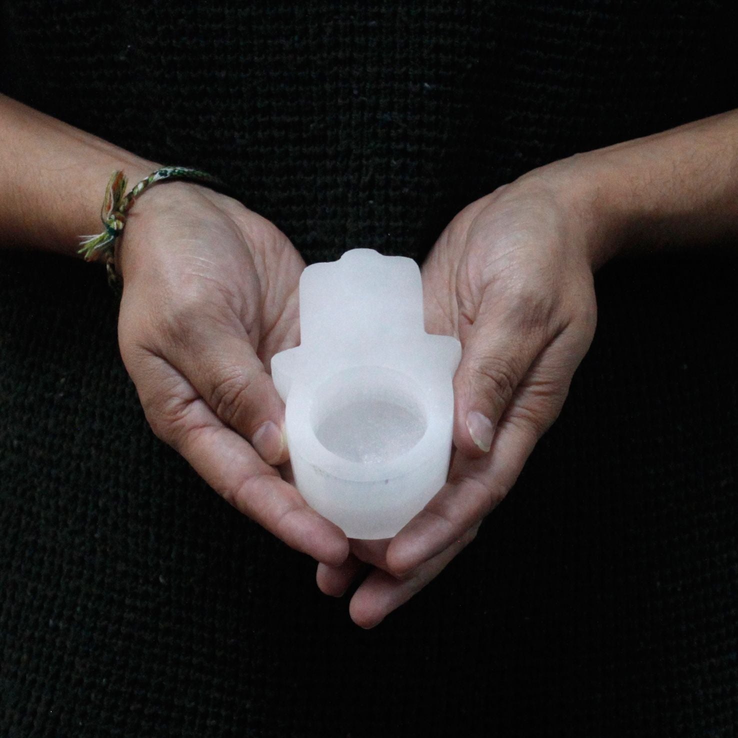 Photophore selenite hamsa tenu en main montrant sa taille compacte et son design protecteur
