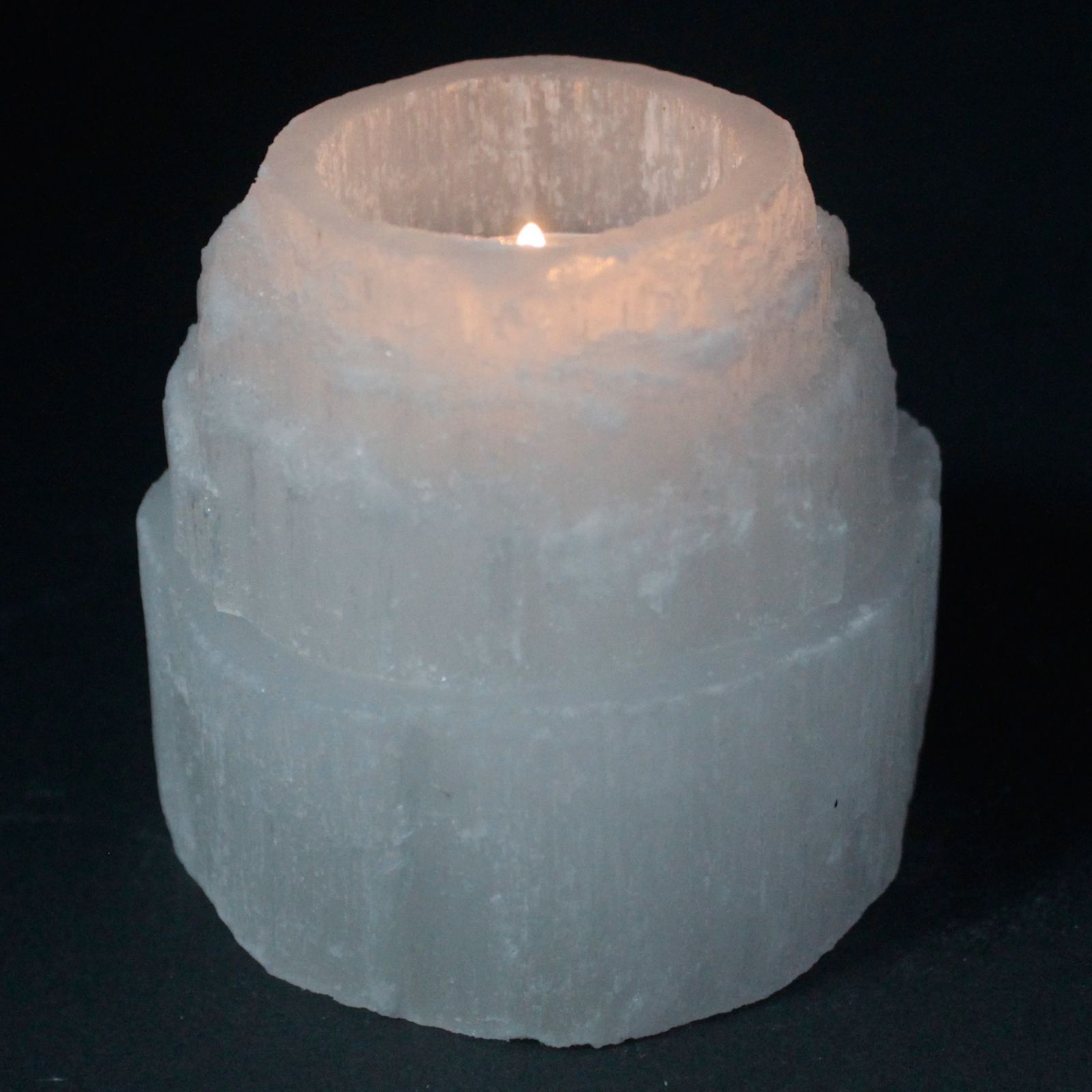 Photophore en selenite forme montagne avec bougie allumee diffusant une lumiere douce et apaisante