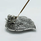 Porte-encens feuille en métal avec éléphant sculpté tenant un bâton d’encens, parfait pour méditation, purification énergétique et espace bien-être.