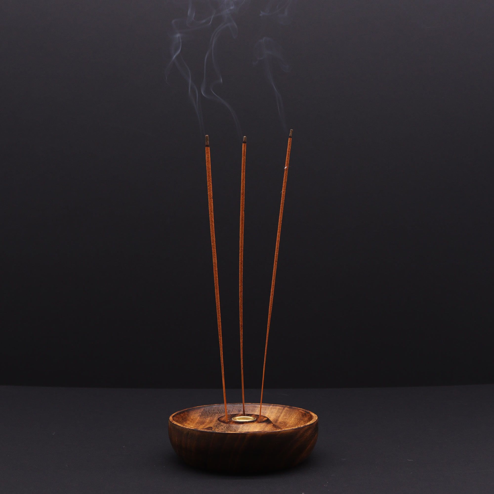 porte encens en bois naturel avec trois bâtons d encens allumés diffusant une fumée apaisante dans une ambiance méditation