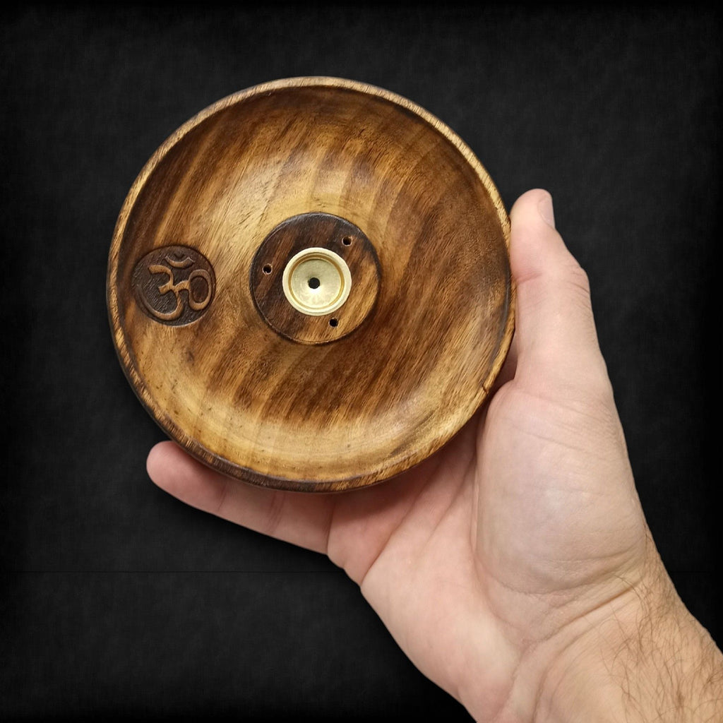 porte encens rond en bois naturel avec symbole om gravé tenu dans la main montrant sa fabrication artisanale et son support pour encens