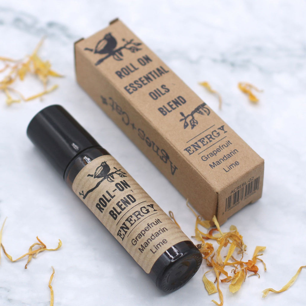 Roll-on d’huiles essentielles energie 10 ml posé avec son étui carton sur fond clair – mélange aromathérapie relaxation