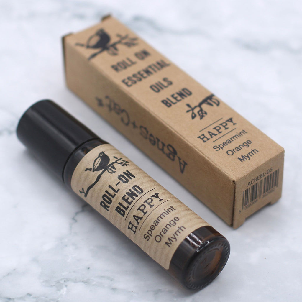 Roll-on d’huiles essentielles happy 10 ml posé avec son étui carton sur fond clair – mélange aromathérapie relaxation